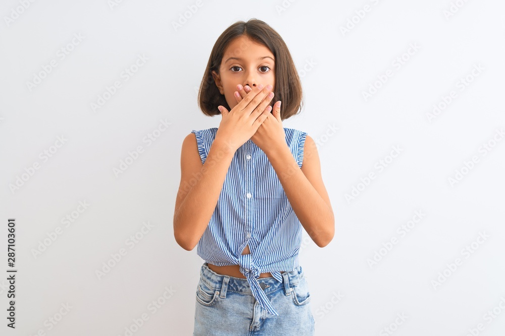 Young beautiful child girl wearing blue casual shirt standing over isolated white background shocked covering mouth with hands for mistake. Secret concept. Young beautiful child girl wearing blue casual shirt standing over isolated white background shocked covering mouth with hands for mistake. Secret concept.
