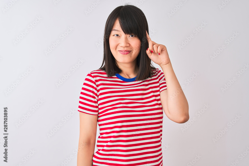 Young beautiful chinese woman wearing red striped t-shirt over isolated white background Smiling pointing to head with one finger, great idea or thought, good memory Young beautiful chinese woman wearing red striped t-shirt over isolated white background Smiling pointing to head with one finger, great idea or thought, good memory