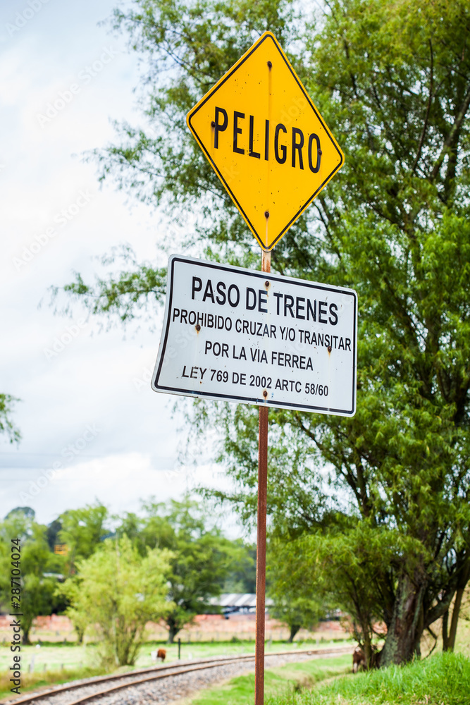Warning sign in spanish stating do not cross or transit along the train rails