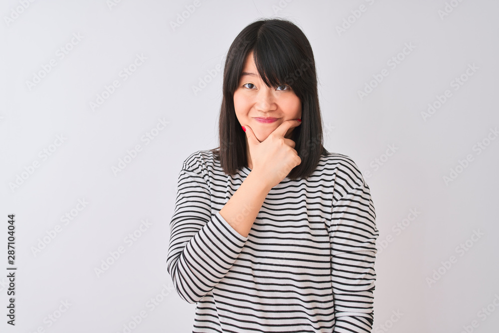 Young beautiful chinese woman wearing black striped t-shirt over isolated white background looking confident at the camera with smile with crossed arms and hand raised on chin. Thinking positive. Young beautiful chinese woman wearing black striped t-shirt over isolated white background looking confident at the camera with smile with crossed arms and hand raised on chin. Thinking positive.