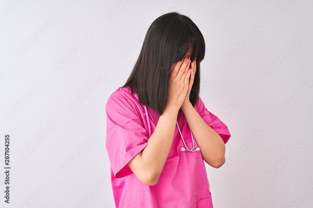 Young beautiful Chinese nurse woman wearing stethoscope over isolated white background with sad expression covering face with hands while crying. Depression concept. Young beautiful Chinese nurse woman wearing stethoscope over isolated white background with sad expression covering face with hands while crying. Depression concept.