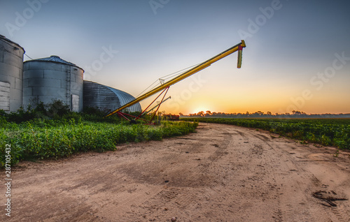 Early morning on a farm with silos and grain augers. photo