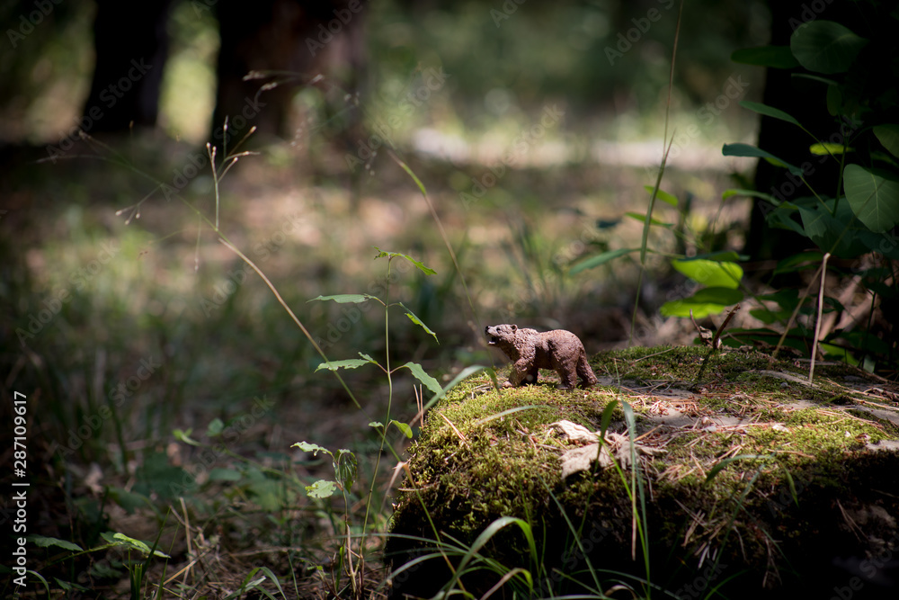 Brown bear walking in forest. Mini bear figure (or toy bear) at the park.