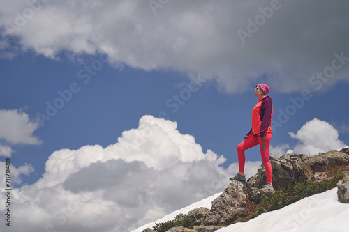 Portrait of hiking woman in red at the beautiful mountains background.