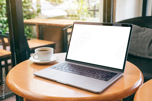 Mockup image of laptop computer with blank white desktop screen with coffee cup on wooden table