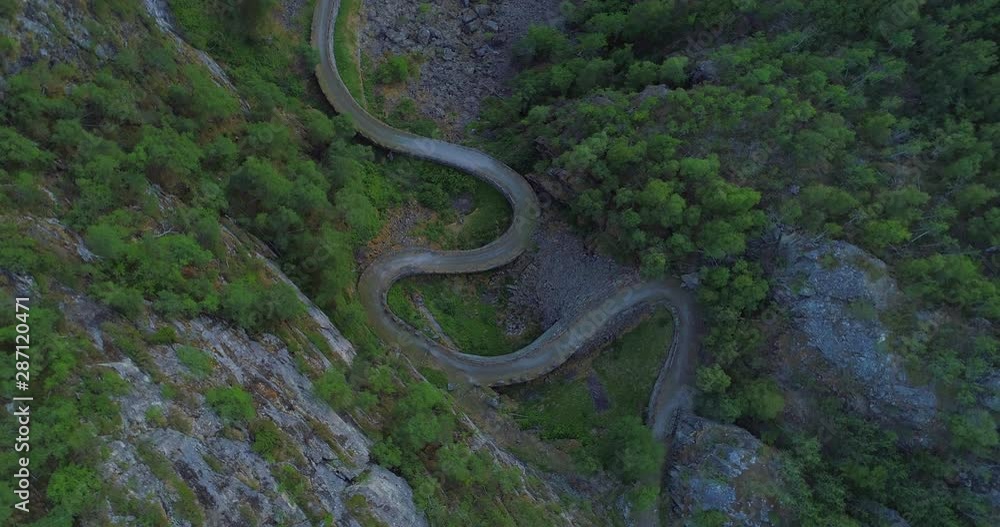 Aerial: Drone moving up over winding road by trees - Borgund, Norway Aerial: Drone moving up over winding road by trees - Borgund, Norway