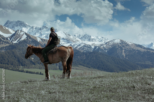 Man on the horse looking at the mountains