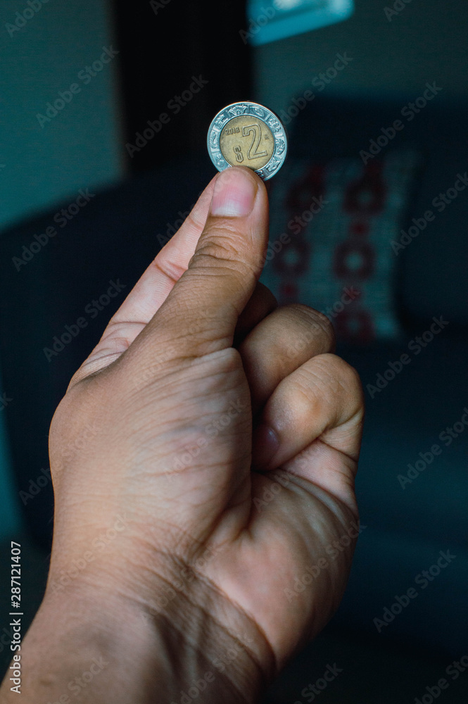 Monedas en la palma de la mano. Pesos mexicanos sobre la mano de hombre adulto. Mano aislada mostrando moneda de 2 (dos) pesos mexicanos