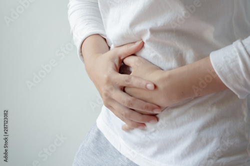 Young woman with white t-shirt suffering from abdominal pain.Chronic gastritis or abdomen bloating and healthcare concept.