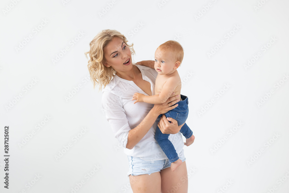 Single parent, motherhood and baby concept - Cheerful mother having fun with her little daughter in the studio, isolated on white background Single parent, motherhood and baby concept - Cheerful mother having fun with her little daughter in the studio, isolated on white background