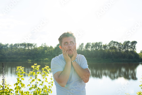 Silly man making funny face or grimace over nature background photo