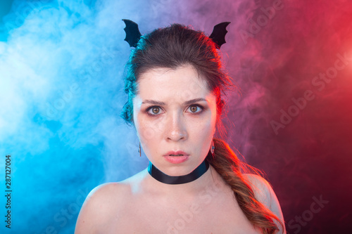 Dark fashion, halloween and people concept - gothic woman in bat ears over the dark background