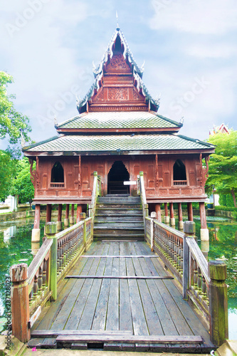 The wooden Tripitaka Library (Ho Trai) that was designed to sit on the stilts in the middle of the pool to prevent the materials from insects (ants and termites) at Wat (temple) Thung Si Mueang. photo