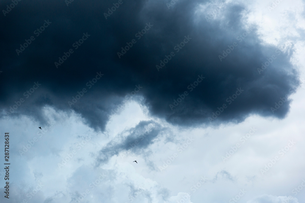 Dark ominous cloud hanging above with birds flying past. Dark ominous cloud hanging above with birds flying past.