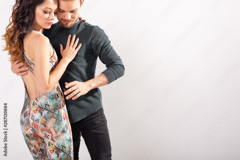 Naklejka premium Young couple dancing latin dance bachata, merengue, salsa, kizomba. Two elegance pose over white background with copy space