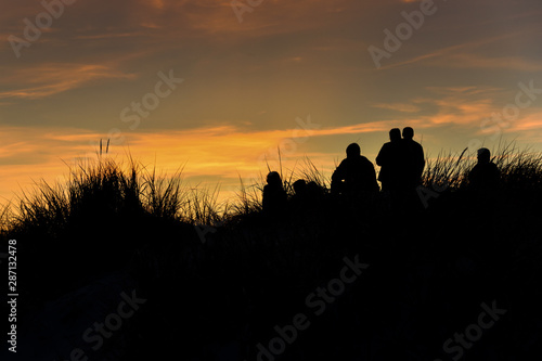 Silhouettes on dunes by Baltic sea in sunset time.