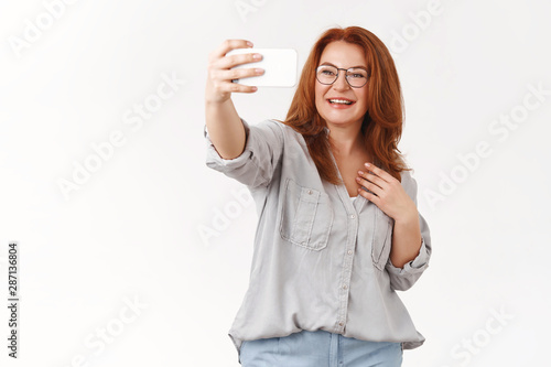 Φωτογραφία Cheerful stylish redhead middle aged 45s woman wear glasses extend arm hold smar