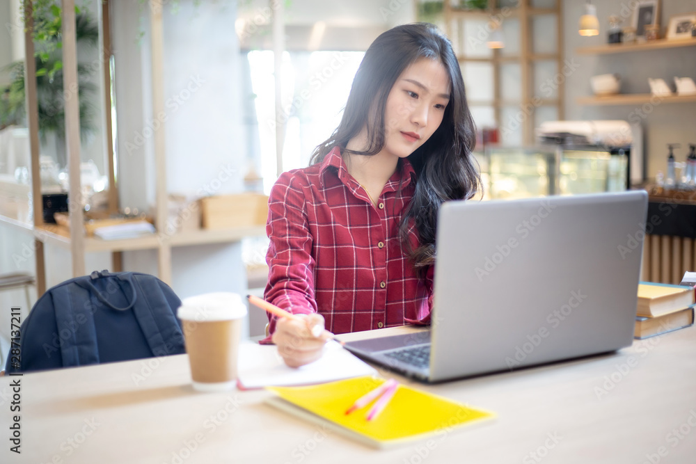 Young Asian woman using laptop computer and tablet PC to working in the modern co working space Young Asian woman using laptop computer and tablet PC to working in the modern co working space