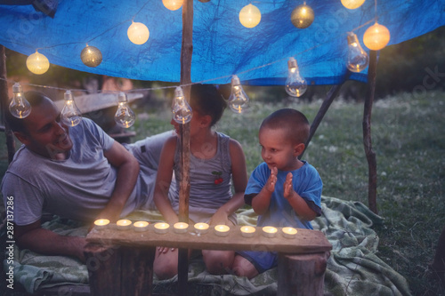 Kids making a small tent with candles and lampions in the backyard.