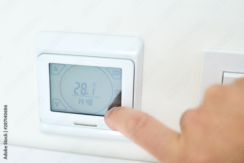 Men hand setting temperature on the underfloor heating control panel Men hand setting temperature on the underfloor heating control panel