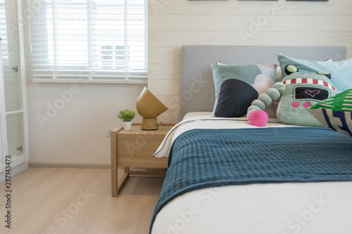 modern kid's bedroom with green, blue and robot doll pillows on it. 