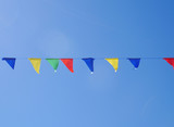 Yellow, green, red, blue triangular flags hang parallel to the blue sky.