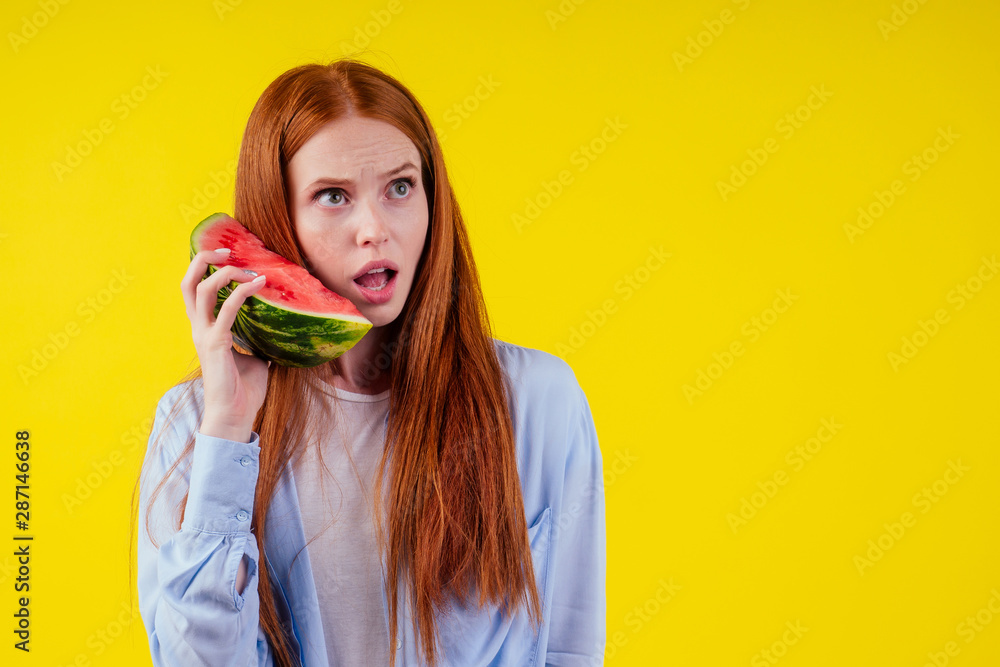 crazy redhaired ginger woman with watermelon imagine that she talking by phone in yellow background studio wall crazy redhaired ginger woman with watermelon imagine that she talking by phone in yellow background studio wall