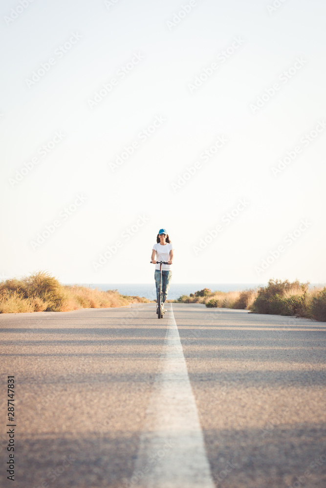 Woman riding an electric kick scooter on a lonely road