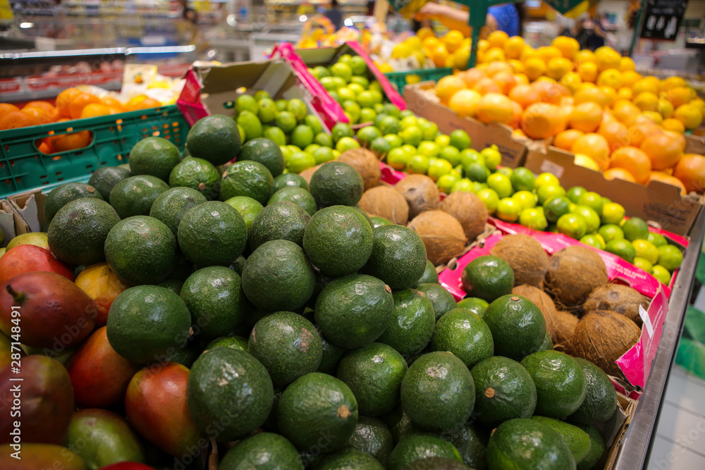 Avocados, coconuts, limes, grapefruits, oranges and mangos on the fruits and vegetables aisle in a store.