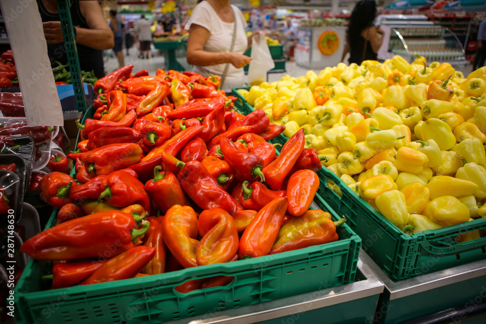 Red and yellow sweet peppers on the fruits and vegetables aisle in a store