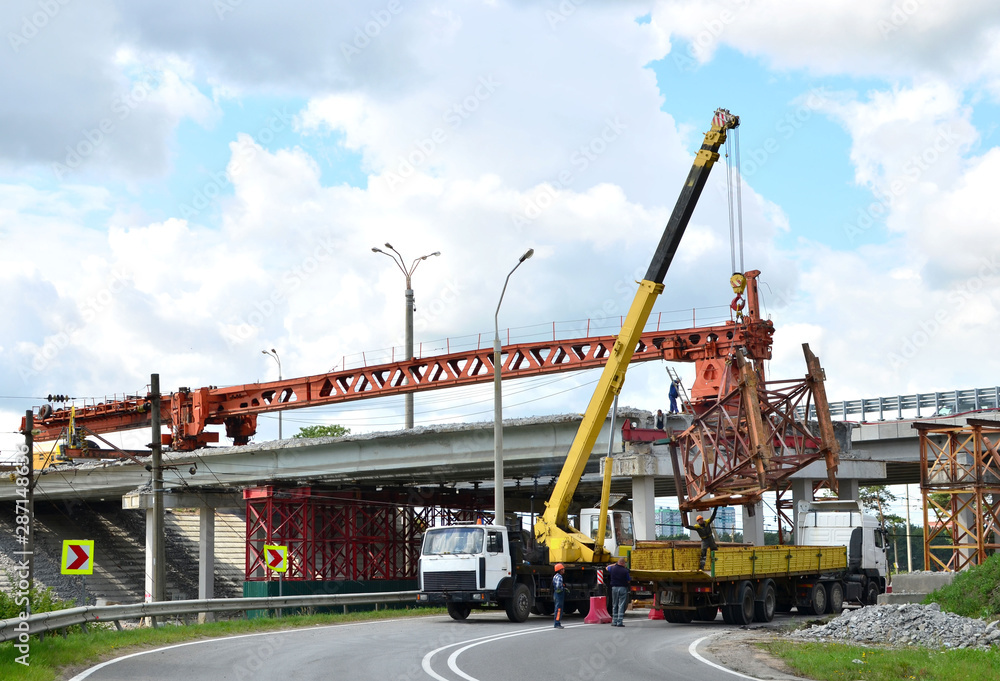 Truck crane working on a construction site. Loading cargo on a truck tractor. Reconstruction and construction of the automobile bridge, replacement of concrete slabs. Workers control work and loading