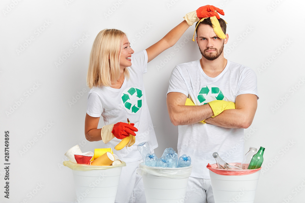 young funny blonde cheerful girl having fun with banana while sorting waste with her frustrated friend , close uop photo. entertainment . young funny blonde cheerful girl having fun with banana while sorting waste with her frustrated friend , close uop photo. entertainment .