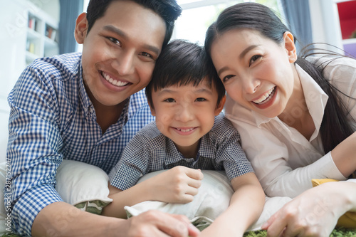 happy asian family spending time together on sofa in living room. family and home concept