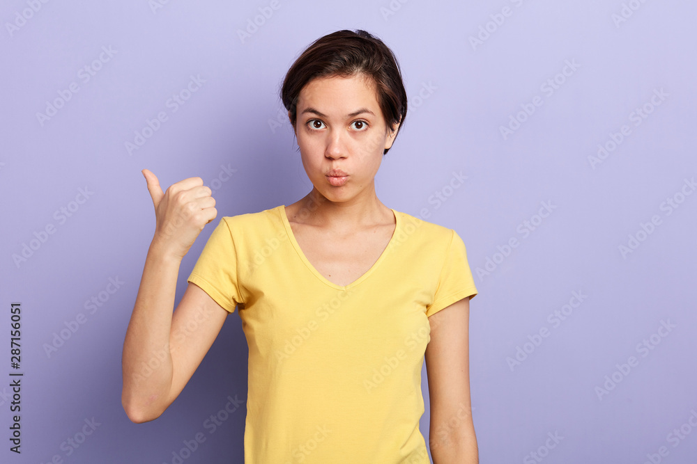 emotional attractive young serious woman pointing copyspace with her thumb.place for advert. copy space emotional attractive young serious woman pointing copyspace with her thumb.place for advert. copy space