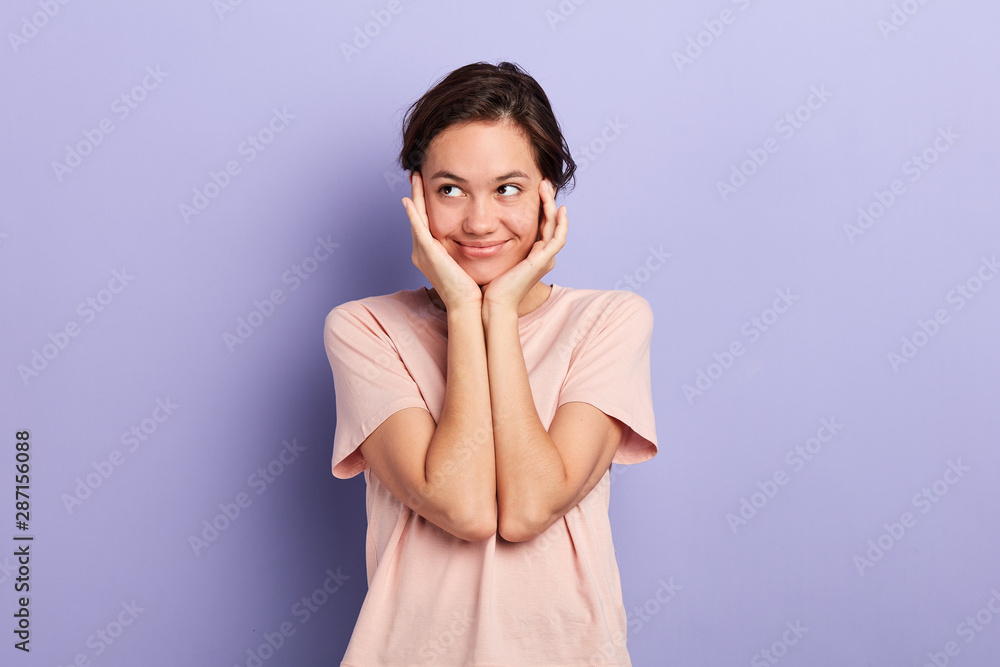 smling cunning sly lovely girl touching cheeks with palms looking aside isolated over blue background. close up portrait, studio shot. plan , idea. copy space. love, feeling, emotion smling cunning sly lovely girl touching cheeks with palms looking aside isolated over blue background. close up portrait, studio shot. plan , idea. copy space. love, feeling, emotion