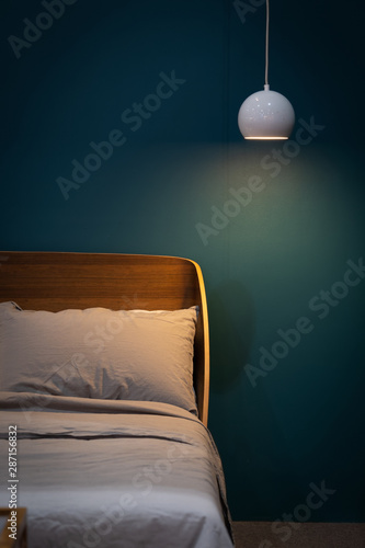 White bed and gray pillow with wooden headboard against dark blue bedroom