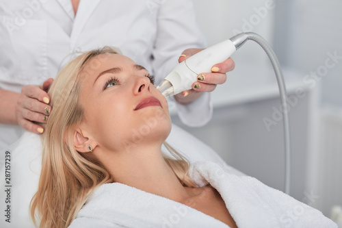 Tableau sur toile young fair-haired woman cleansing and peeling her face, close up photo