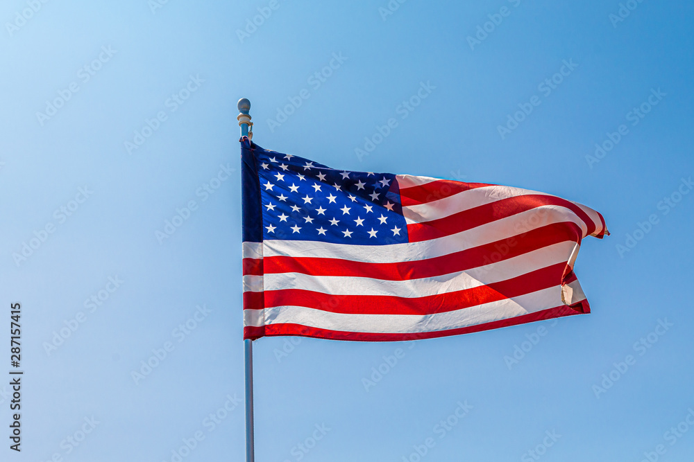 The American Flag Unfurling in Wind on Clear Blue Sky