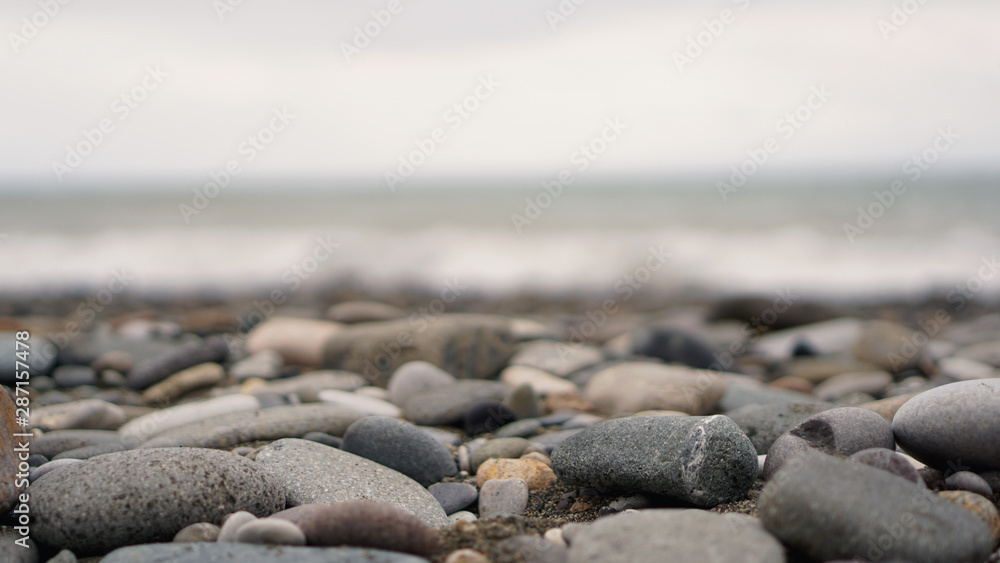 Pebble stones on the shore close up in the blurry light in the distance background. Pebble stones on the shore close up in the blurry light in the distance background.