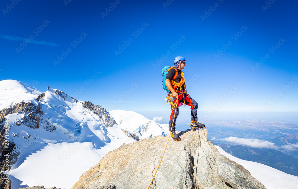 Alpinist mountaineer standing rock cliff mountain summit.