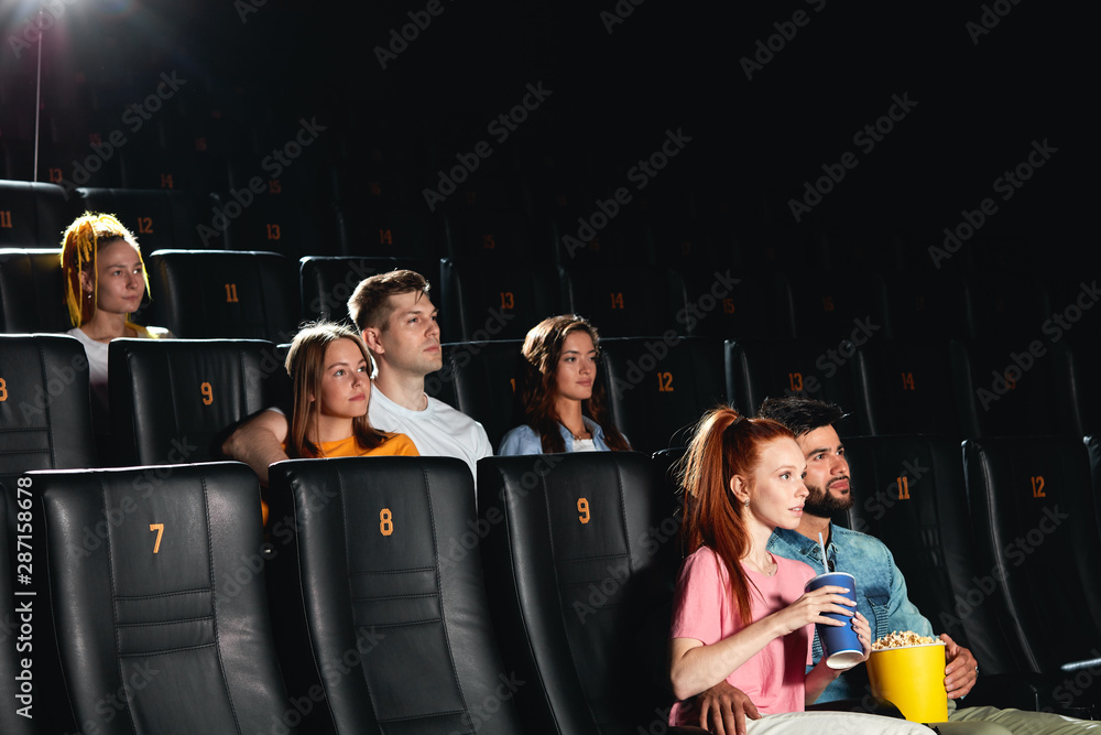 a group of people watching high-quality movie on a big screen, surrounded by impressive sound . side view photo