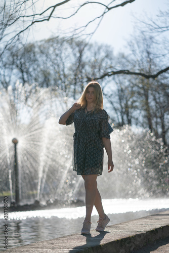 pretty caucasian plus size girl walking near the fountain in the city park