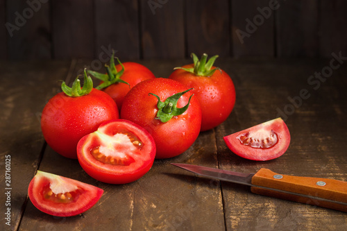 red ripe tomatoes whole and halves knife on wooden table