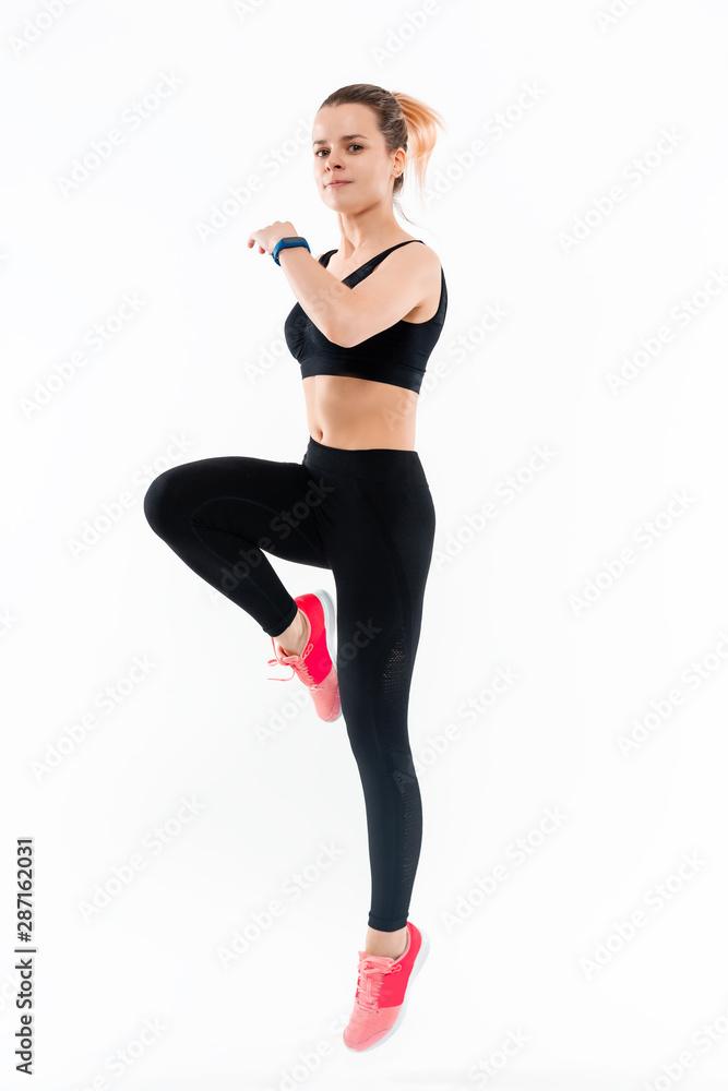 Young sporty blond woman in a black sportswear jumping isolated over white background. Sport activity Young sporty blond woman in a black sportswear jumping isolated over white background. Sport activity