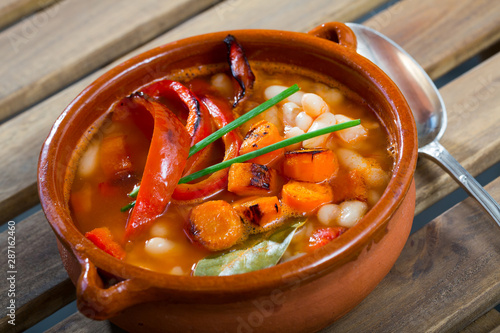 Soup of bean with boiled carrots, pepper and greens, served in bowl photo