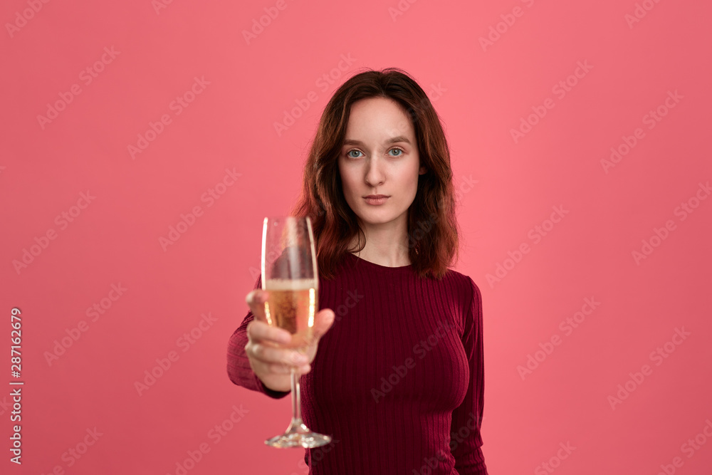 Excited pretty brunette girl holding wineglass of sparkling champagne standing isolated on a dark pink background and smiling at the camera. Excited pretty brunette girl holding wineglass of sparkling champagne standing isolated on a dark pink background and smiling at the camera.