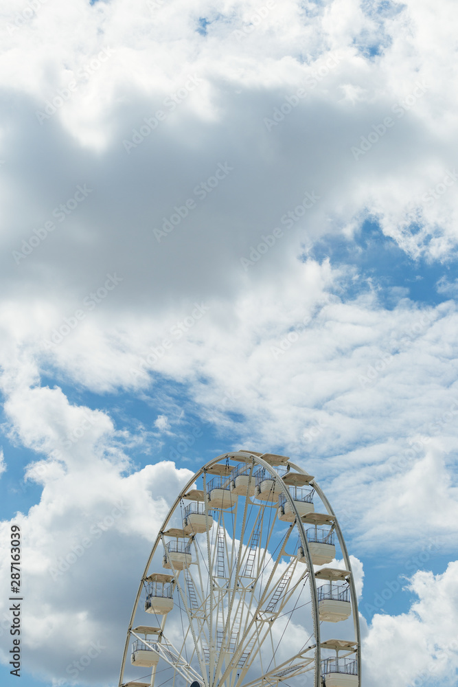Ferris wheel on the blue cloudy sky. Background concept of happy holidays time. Ferris wheel on the blue cloudy sky. Background concept of happy holidays time.