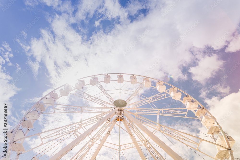 Ferris wheel on the colorful cloudy sky. Background concept of happy holidays time.