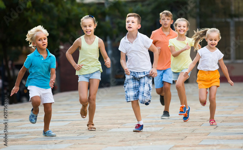 kids actively playing and running together on street on summer day