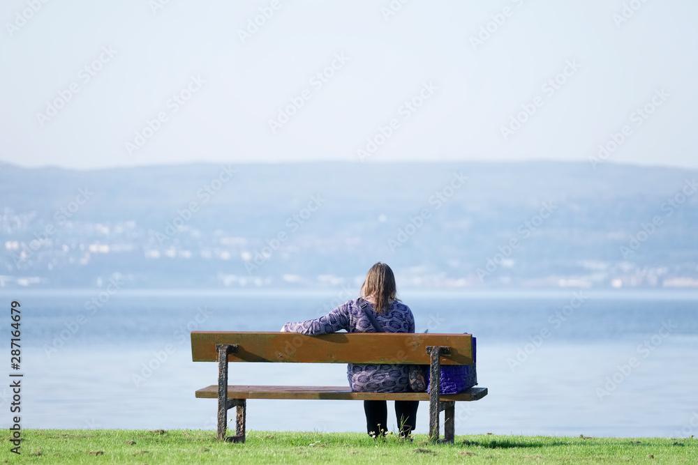 Single lady lonely on park bench at the sea enjoy peace and quiet for mindfulness meditation